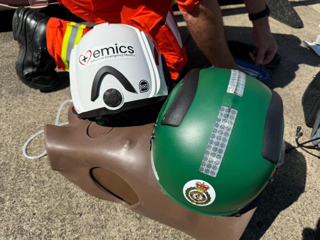 EMICS and ambulance service helmets on a training mannequin with a responder in hi-vis overalls